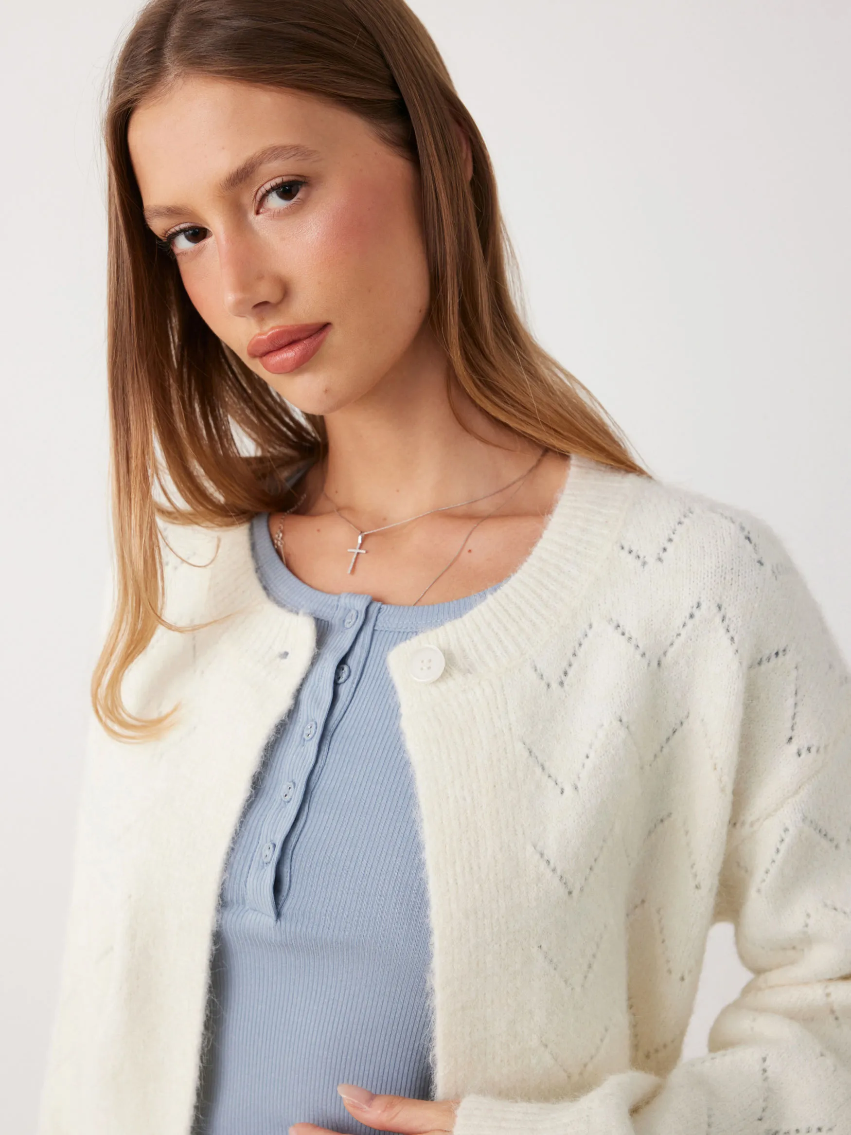 Close-up detail shot of a fine knit top showing clean stitch definition, fabric drape, and quality finishing