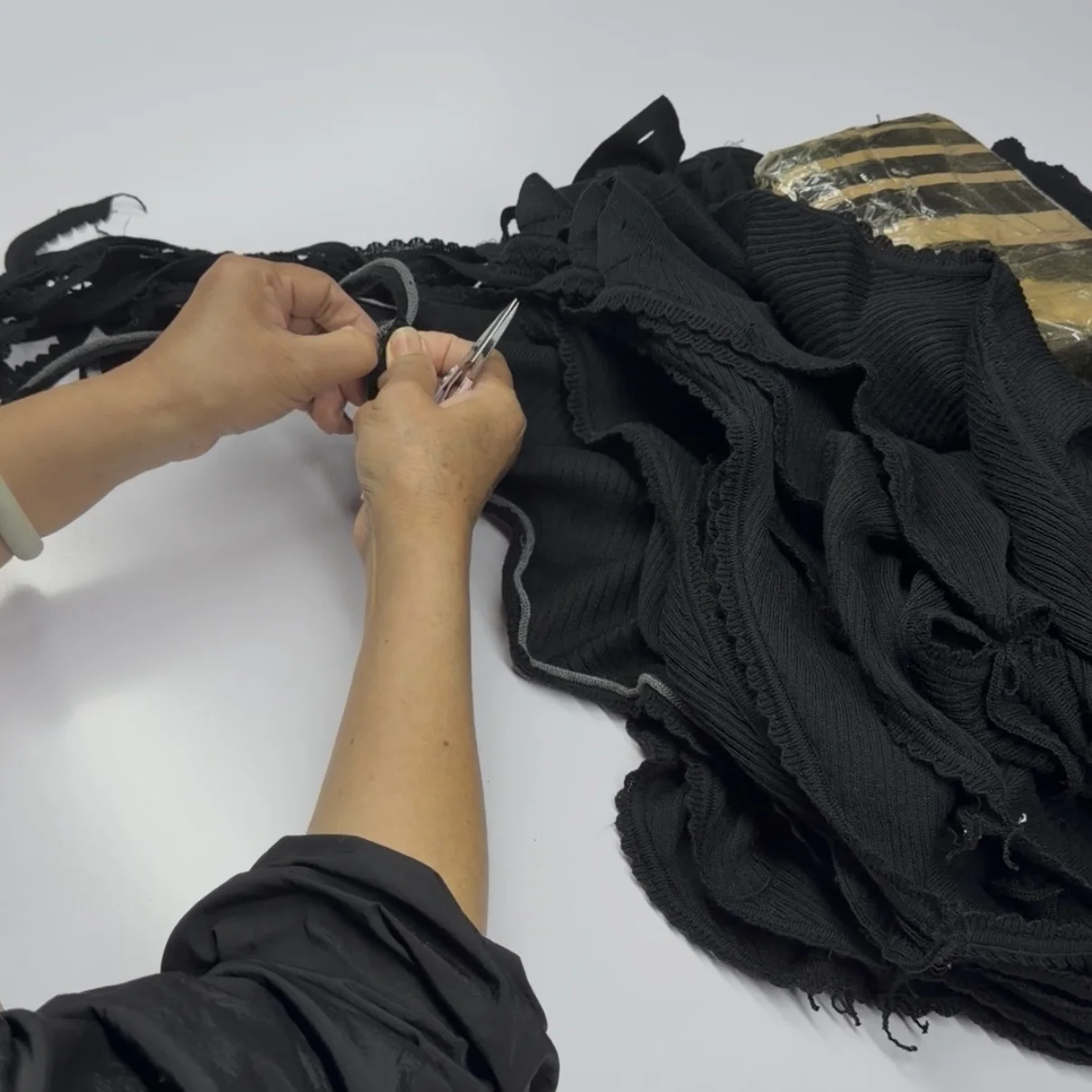 Skilled worker operating a specialized linking machine to join knitted garment pieces with seamless finishing