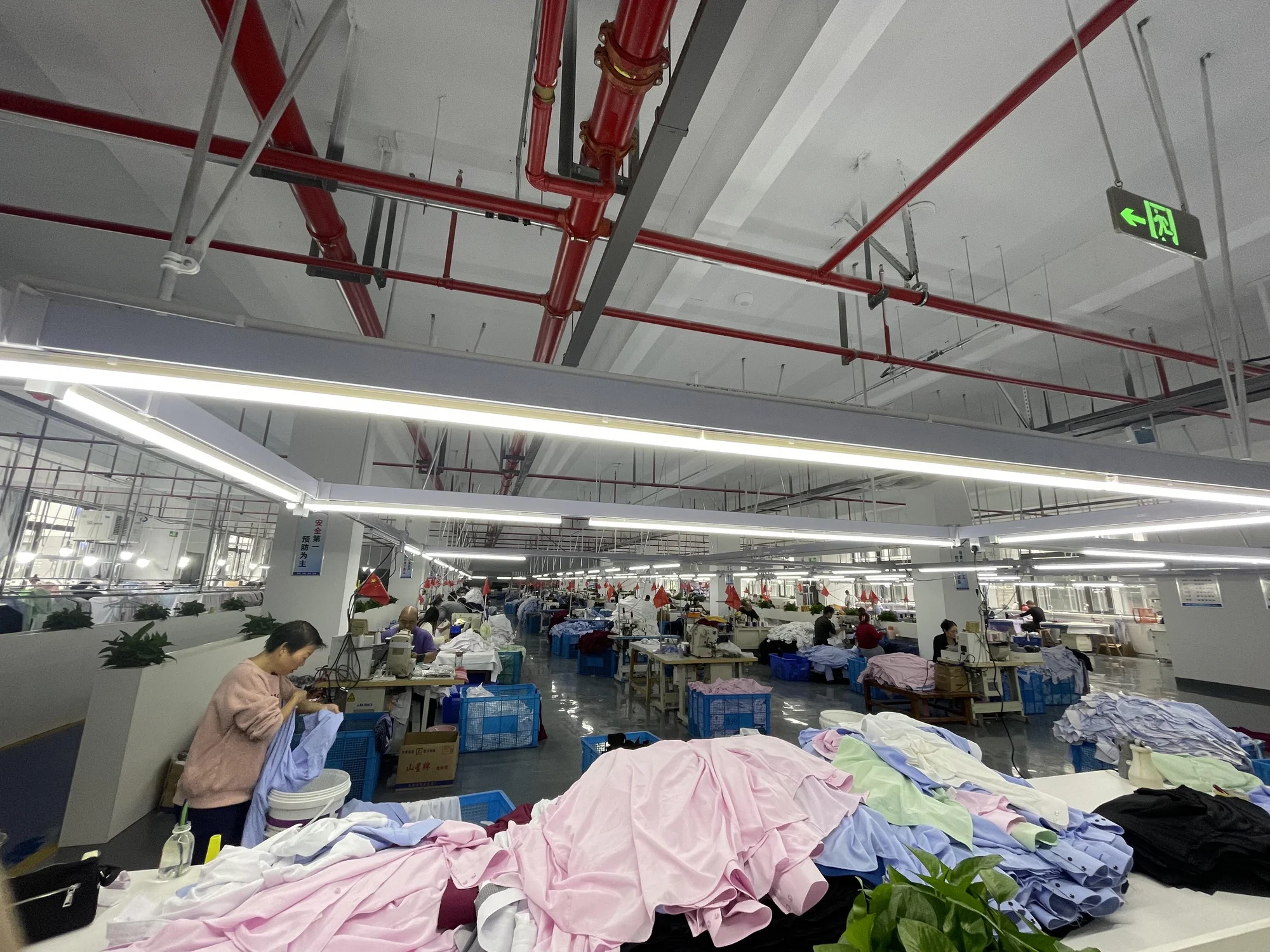 Computerized flat knitting machines by Shima Seiki and Stoll operating in a Shantou knitwear factory, producing sweater panels